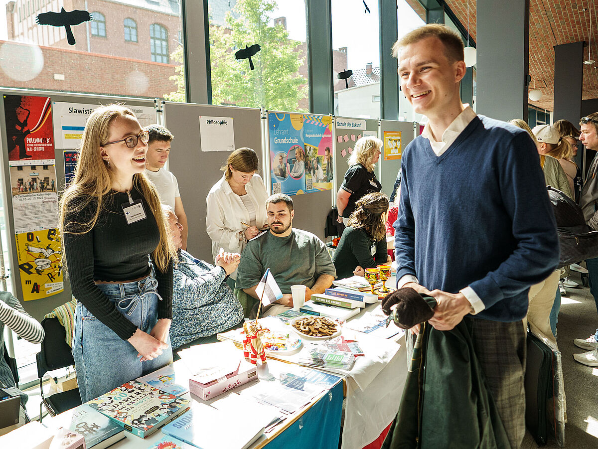 Auf dem Infomarkt an den Hochschulinfotagen unterhalten sich Personen und die lachen auf dem Bild.