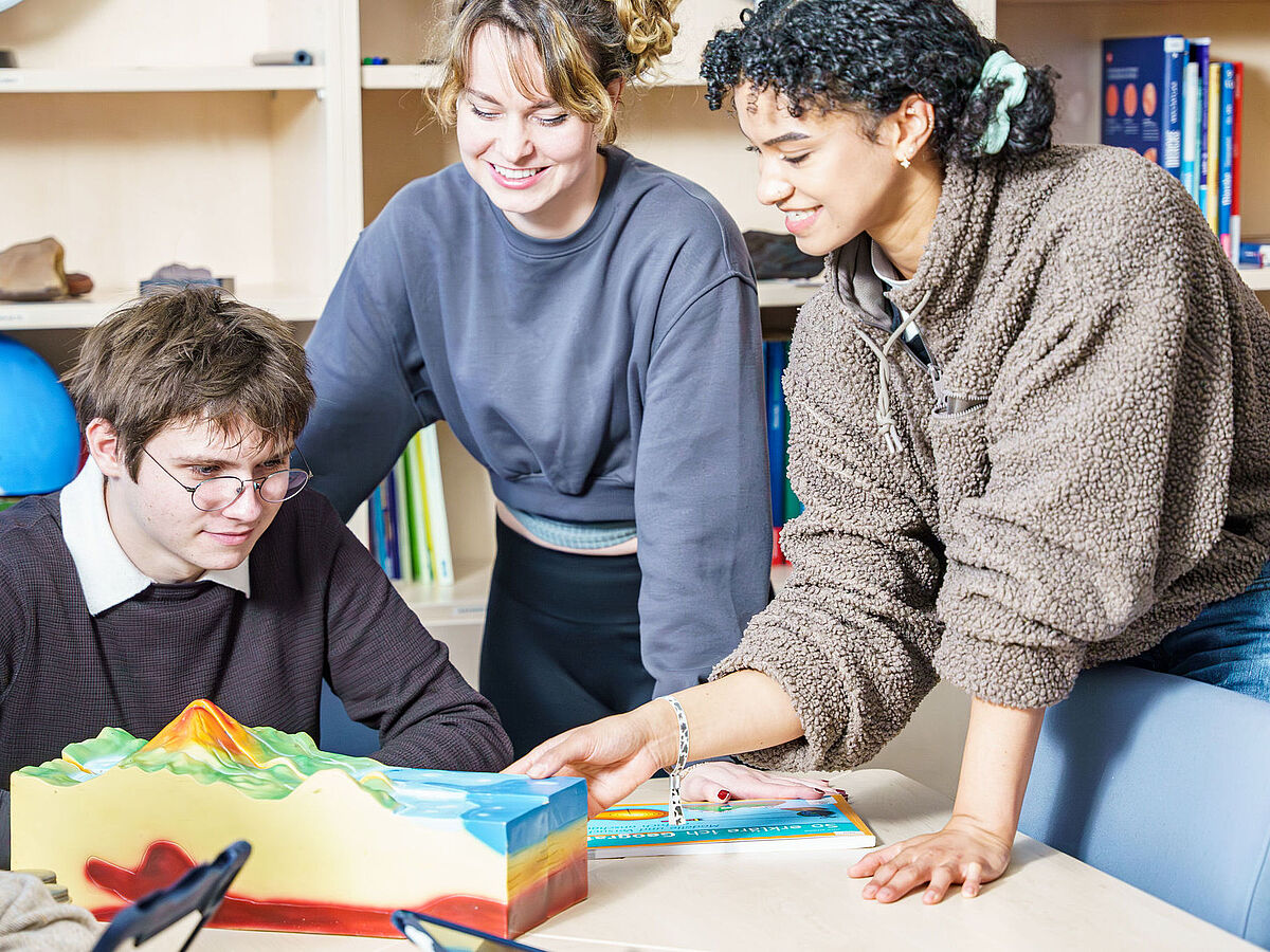 Studierende schauen sich im Seminar verschiedene Unterrichtsmaterialien an.