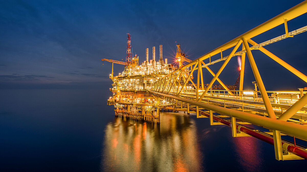 Eine industrielle Offshore-Öl- und Gasbohrplattform bei Nacht im Golf von Thailand.